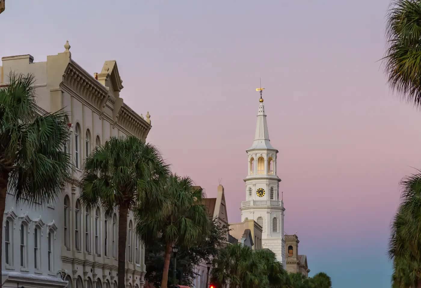 Broad Street in downtown Charleston, SC at dusk, palmettos and historic storefronts leading to the St. Michael's Church steeple